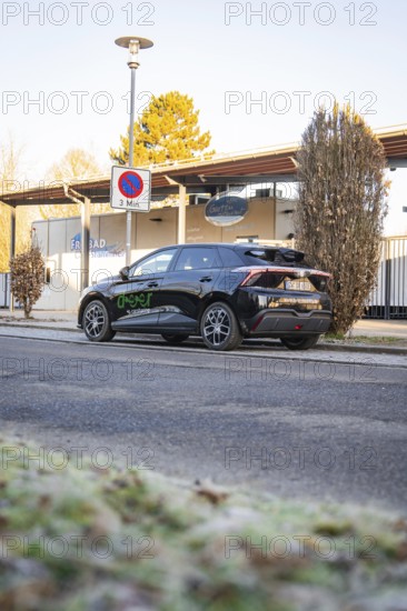 Car parked at the edge of a parking lot with trees and a building in the background, MG4 electric car, Deer E- Carsharing, Calw, Germany