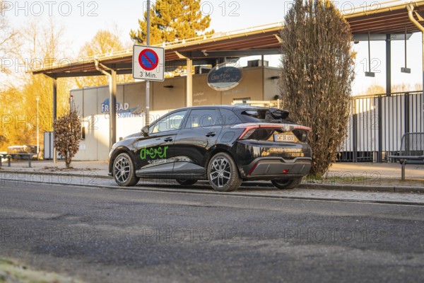 Car parked near an outdoor pool building with evening lights and signs, MG4 electric car, Deer e-Carsharing, Calw, Germany