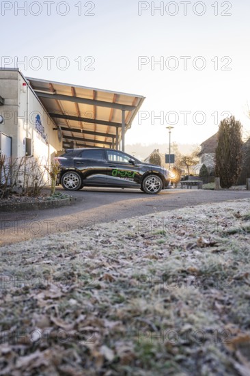 Modern electric car in front of a building on frosty terrain on a clear winter morning, MG4 electric car, Deer e-Carsharing, Calw, Germany