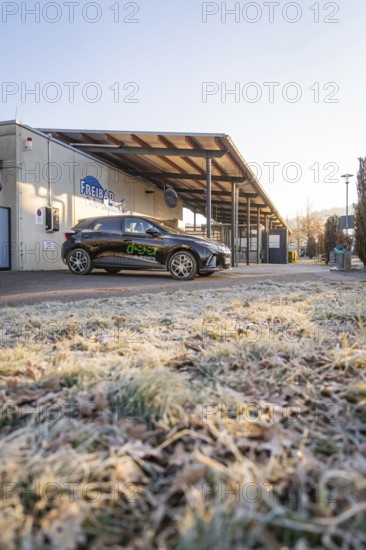 Parked electric car in front of a building on frosty ground on a clear winter morning, MG4 electric car, Deer e-Carsharing, Calw, Germany