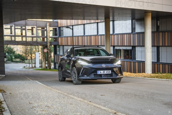 Car in an urban environment in front of a modern office building, contemporary architecture, MG4 electric car, Deer e-Carsharing, Calw, Germany