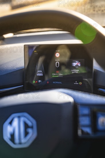Vehicle display next to steering wheel with brand logo, showing speed and charging information, MG4 electric car, Deer e-Carsharing, Calw, Germany