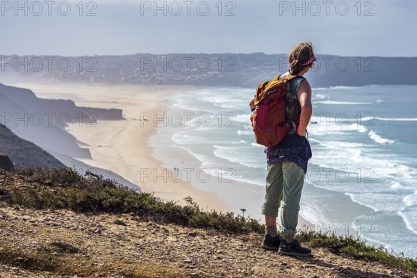 Woman with backpack, above beach Prai de Bordeira north of village Carrapateira, coast of western Algarve, Portugal