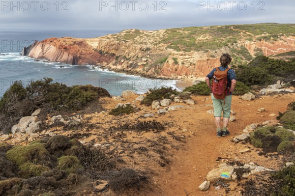 Hiking woman, view over cliff, Fishermens Trail, Rosa Vicentina, western Algarve just north of cape Cabo de Sao Vicente, Portugal