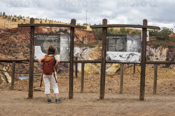 Woman reading explanatory panel, entrance to Mina de Sao Domingos, historic copper open-pit mine, Portugal