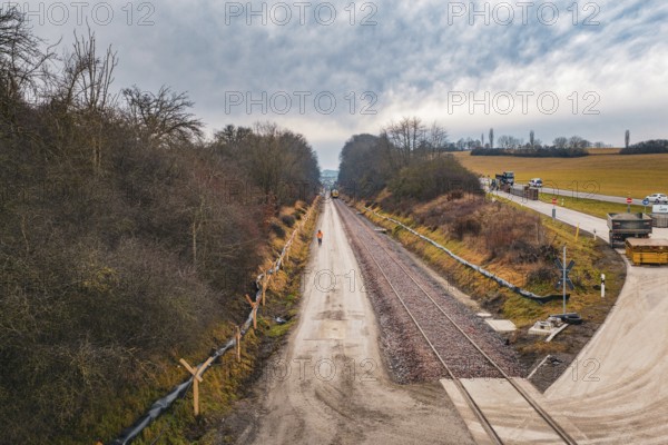 Construction site along a rail line surrounded by bare autumn forest, tamping machine used on the Hermann Hessebahn construction site, Calw, Germany