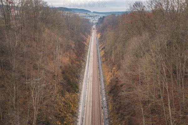 Rail line snakes through hilly autumn landscape with bare trees, using a tamping machine at the Hermann Hessebahn construction site, Calw, Germany