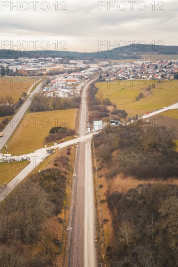 Aerial view of a railway line through snowy fields near a village, using a tamping machine at the Hermann Hessebahn construction site, Calw, Germany