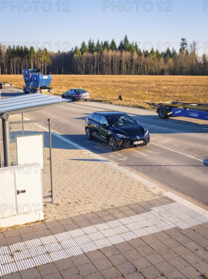 A car moves on a road flanked by other vehicles and trees, MG4 electric car, Deer e-Carsharing, Calw, Germany
