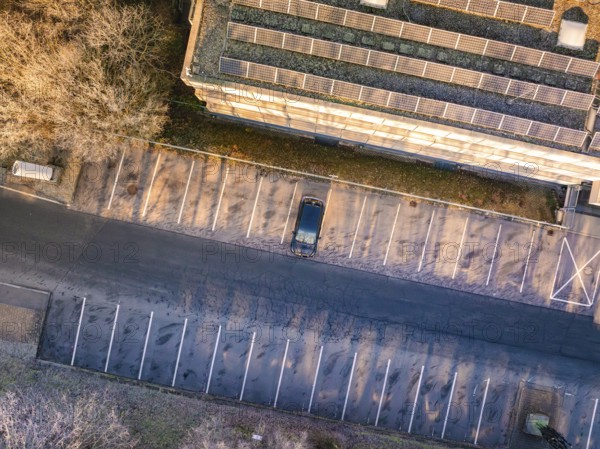 Aerial view of a parking lot with a single car, next to a building with solar panels, MG4 electric car, Deer e-Carsharing, Calw, Germany