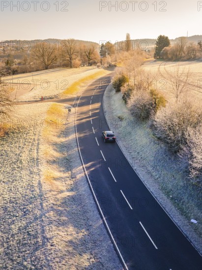 Car driving alone on a winding country road surrounded by frosty landscape, MG4 electric car, deer e-car sharing, Calw, Germany