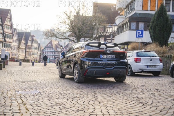 Car parked on paved street in an old town, half-timbered houses in the background, MG4 electric car, deer e-car sharing, Calw, Germany
