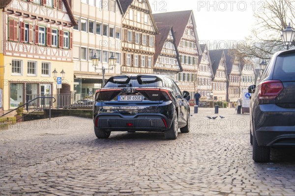 Car drives through a paved street surrounded by historic half-timbered houses, MG4 electric car, deer e-car sharing, Calw, Germany