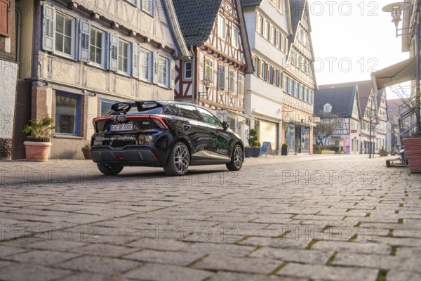 Car drives quietly through a street with traditional architecture and half-timbered houses, MG4 electric car, Deer e-Carsharing, Calw, Germany