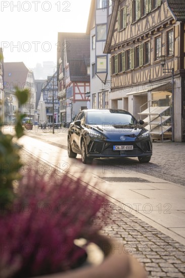 Black car parked on a paved street in a historic town with half-timbered houses in daylight, MG4 electric car, deer e-car sharing, Calw, Germany