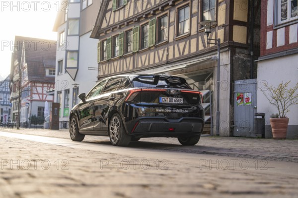 Rear view of a black car in front of historic half-timbered houses, captured in the evening mood, MG4 electric car, Deer e-Carsharing, Calw, Germany