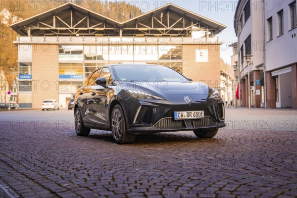 Black car in the city center surrounded by modern architecture and paved roads under blue skies, MG4 electric car, Deer e-Carsharing, Calw, Germany