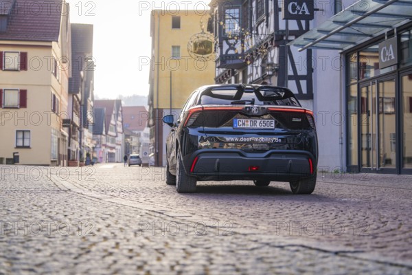 A car is parked on a cobblestone street in a picturesque town with half-timbered houses, MG4 electric car, Deer e-Carsharing, Calw, Germany