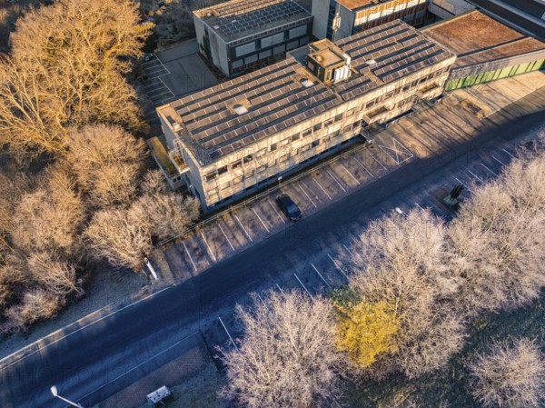 Building complex with empty parking spaces, surrounded by a winter tree landscape, MG4 electric car, deer e-car sharing, Calw, Germany