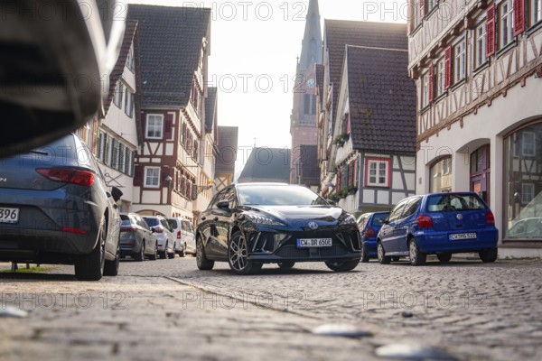 Car in a narrow old town street with half-timbered houses and church in the background, MG4 electric car, Deer e-Carsharing, Calw, Germany