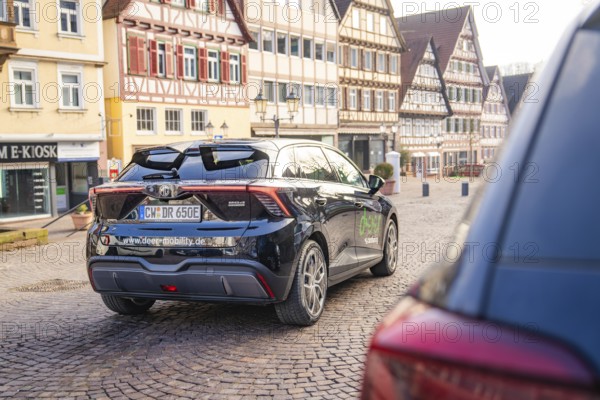 Car in an old town with half-timbered houses and cobblestone streets, MG4 electric car, Deer e-Carsharing, Calw, Germany