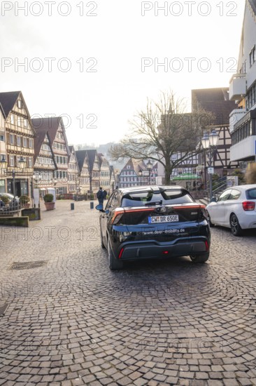 Black car on a paved road between historic half-timbered houses, MG4 electric car, Deer e-Carsharing, Calw, Germany