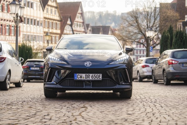 A car in an old town street with half-timbered houses and cobblestones, MG4 electric car, Deer e-Carsharing, Calw, Germany