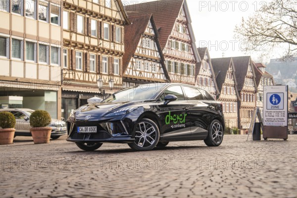 Black car parked in an old town with half-timbered houses and cobblestones, MG4 electric car, deer e-car sharing, Calw, Germany