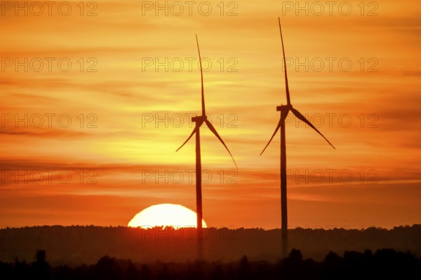 Stemshorn, Lower Saxony, Germany, Two wind turbines stand in the foreground in front of a glowing sunset