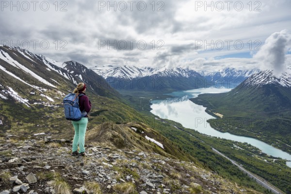 Female mountaineer in front of mountain landscape, Slaughter Ridge Trail, view of snow-covered mountains and turquoise lake Kenai Lake, Cooper Landing, Kenai Peninsula, Alaska, USA