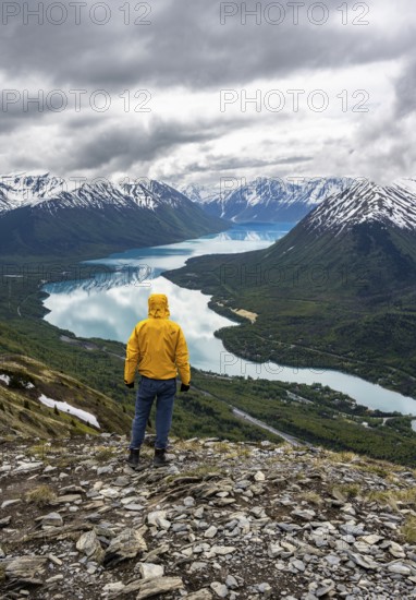 Climber enjoying the view, Slaughter Ridge Trail, view of snowy mountains and turquoise blue Kenai Lake, Cooper Landing, Kenai Peninsula, Alaska, USA