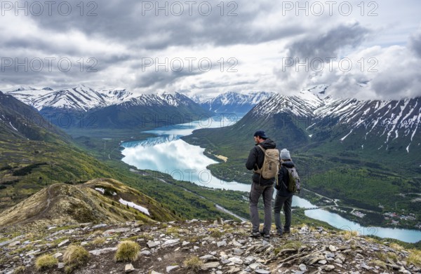 Two mountaineers in front of mountain scenery, Slaughter Ridge Trail, view of snow-covered mountains and turquoise blue Kenai Lake Lake, Cooper Landing, Kenai Peninsula, Alaska, USA