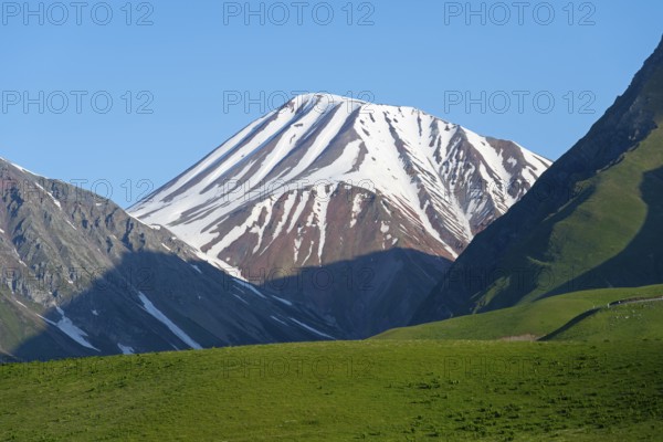 Snowy mountain with shadows cast over green hills, landscape between Kvesheti and Gudauri, Mtskheta-Mtianeti region, Georgian Military Route, High Caucasus, Georgia
