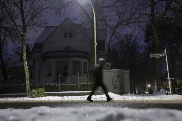 A person walks past a dark villa with an anarchy symbol written on the wall during the large-scale power outage in the Steglitz-Zehlendorf district, Berlin, 06.01.2026