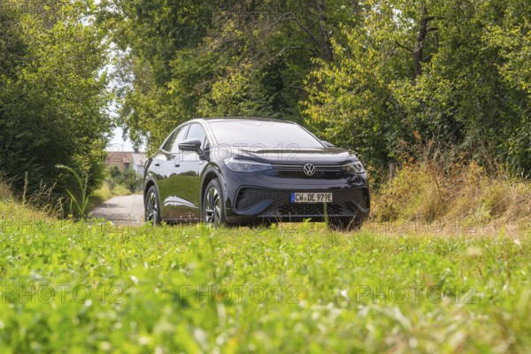 Black car on a country road surrounded by greenery in cloudy sky, VW ID5 electric car, Deer e-Carsharing, Calw, Germany