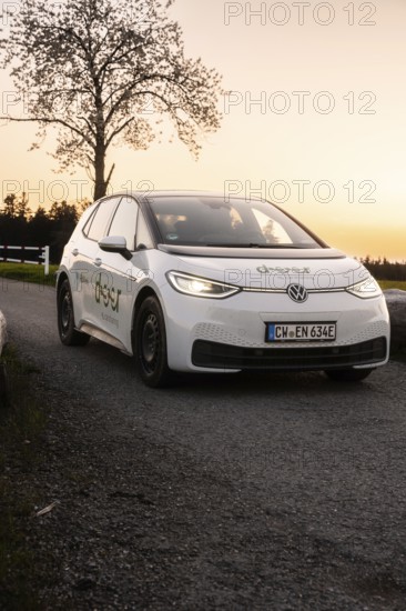 Car at sunset on street, parked with illuminated headlights, VW ID3 electric car, deer e-car sharing, Calw, Germany
