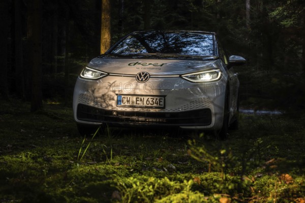 Car at dusk in the forest, headlights glow, mystical atmosphere, VW ID3 electric car, deer e-car sharing, Calw, Germany