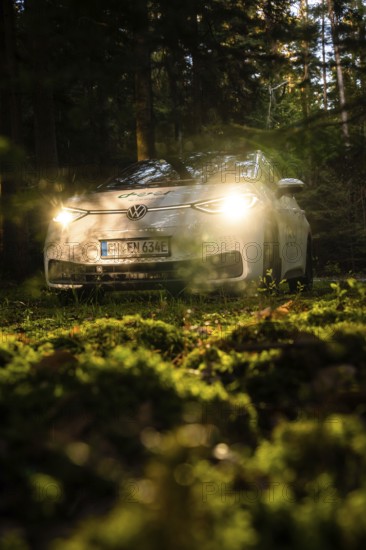 Car in the dark forest, headlights glow on mossy ground, mystical atmosphere, VW ID3 electric car, deer e-car sharing, Calw, Germany