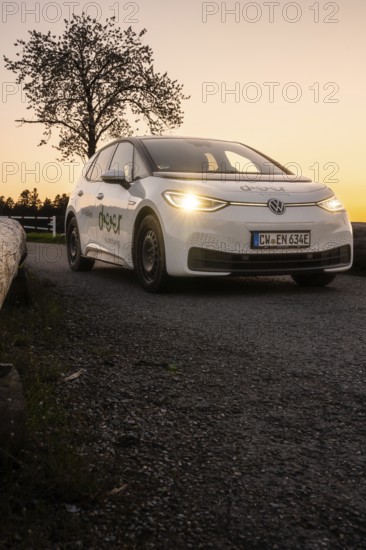 Car driving along a street with glowing headlights in the evening, VW ID3 electric car, Deer e-Carsharing, Calw, Germany