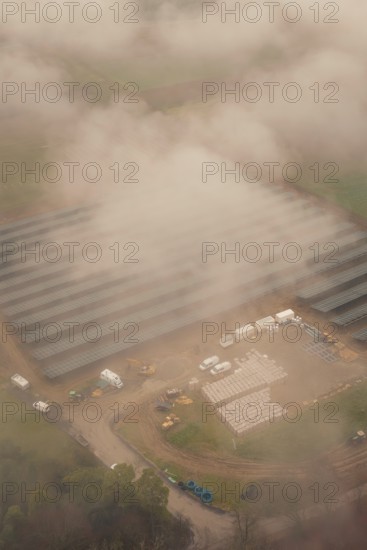Construction site for solar systems, foggy environment with several construction site vehicles, energy revolution, construction of PV open space, Baden-Württemberg, Germany