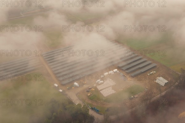 Fog-covered construction site with solar systems, several vehicles visible, energy revolution, construction of PV open space, Baden-Württemberg, Germany