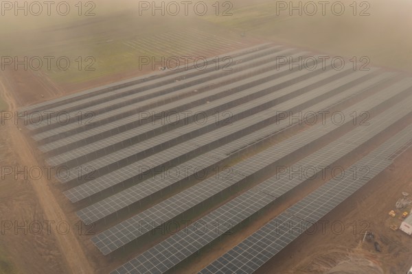 Dense rows of solar panels on foggy field, clear lines and structure, energy revolution, construction of PV open space, Baden-Württemberg, Germany