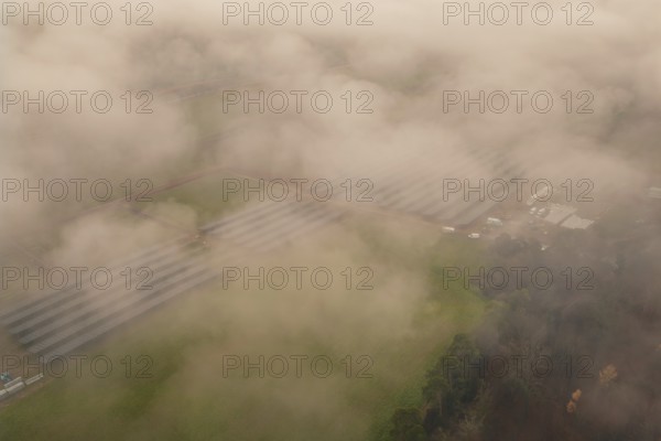 Solar systems in a foggy field landscape, diffuse view through thick fog, energy revolution, construction of PV open space, Baden-Württemberg, Germany