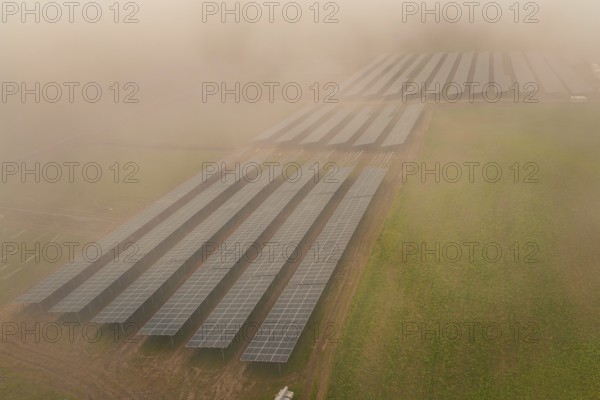 Rows of solar panels spread over foggy field, focus on renewable energy, energy transition, construction of PV open space, Baden-Württemberg, Germany