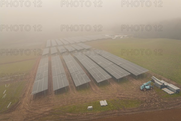 Solar systems in fields in foggy surroundings, distinct structure of solar modules, energy revolution, construction of PV open space, Baden-Württemberg, Germany