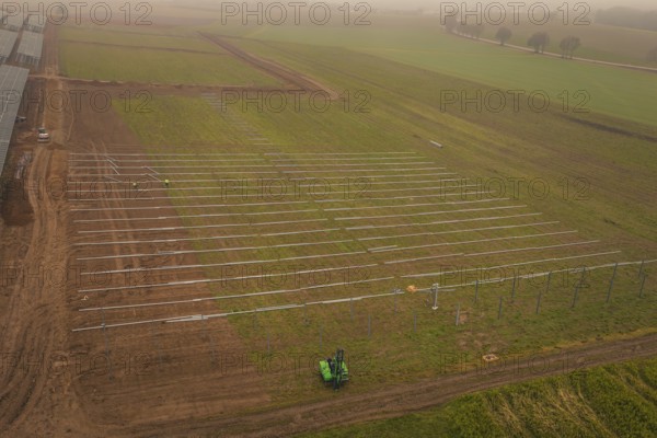 Foggy fields with solar system installation in the foreground, machines in use, energy revolution, construction of PV open space, Baden-Württemberg, Germany