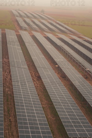 Row of solar panels in a foggy landscape, sustainable energy generation in wide fields, energy revolution, construction of PV open space, Baden-Württemberg, Germany