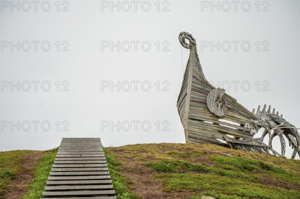 Wooden staircase leads to a sculptural wooden structure on a hill, sculpture by Drakkar Vardø. The Drakkar-Leviathan sculpture was built in summer 2016 by the Taibola Assemble team from Archangelsk Severodvinsk, Vardø, Finnmark, Norway