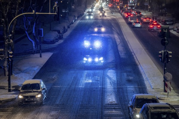 Ambulance, RTW, the Essen professional fire brigade during an emergency trip with flashing lights, winter weather, blowing snow, inner-city road traffic, Alfredstraße, B224, in Essen, North Rhine-Westphalia, Germany