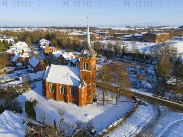 Snowy church with high tower surrounded by snow-covered trees and buildings, aerial view, Trinity Church, Oelsburg, Ilsede municipality, Peine district, Lower Saxony, Germany